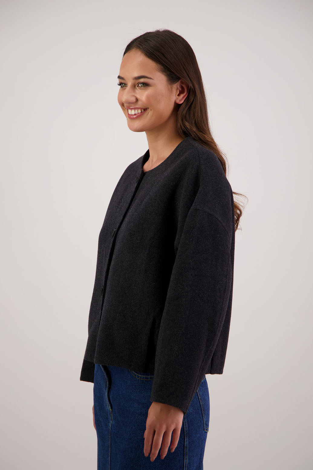 Renee Jacket in Black by Briarwood NZ. Features, no collar, button closure, shaped sleeves, pockets, drop shoulder and dart type pleats on the hem of the jacket
