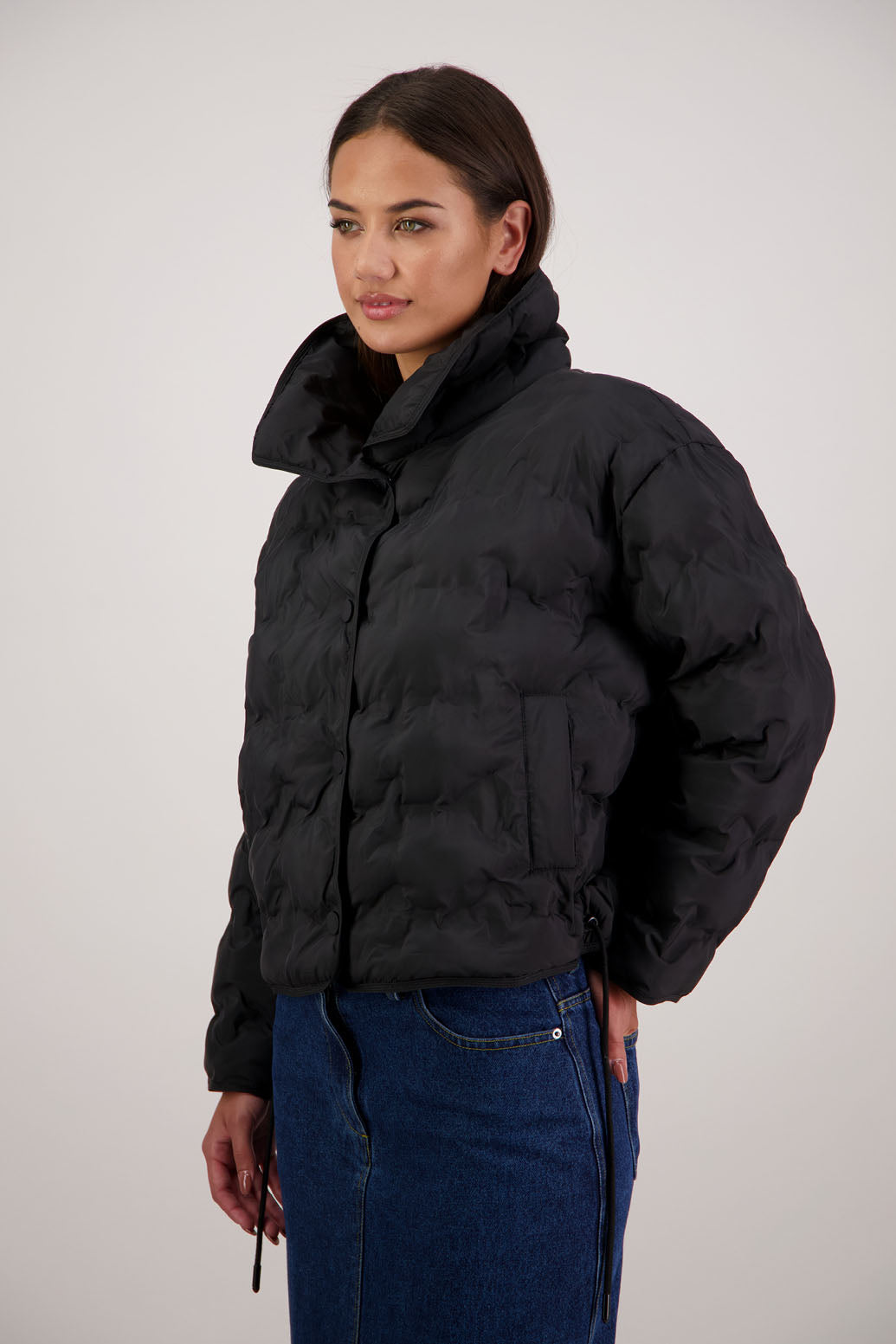 Rhodes Padded Jacket in Black by Briarwood NZ. Features, magnetic dome closures, filled with plush fibres, elastic pull across the back with toggles to hold it in place, high collar with invisible magnetic closure, pockets