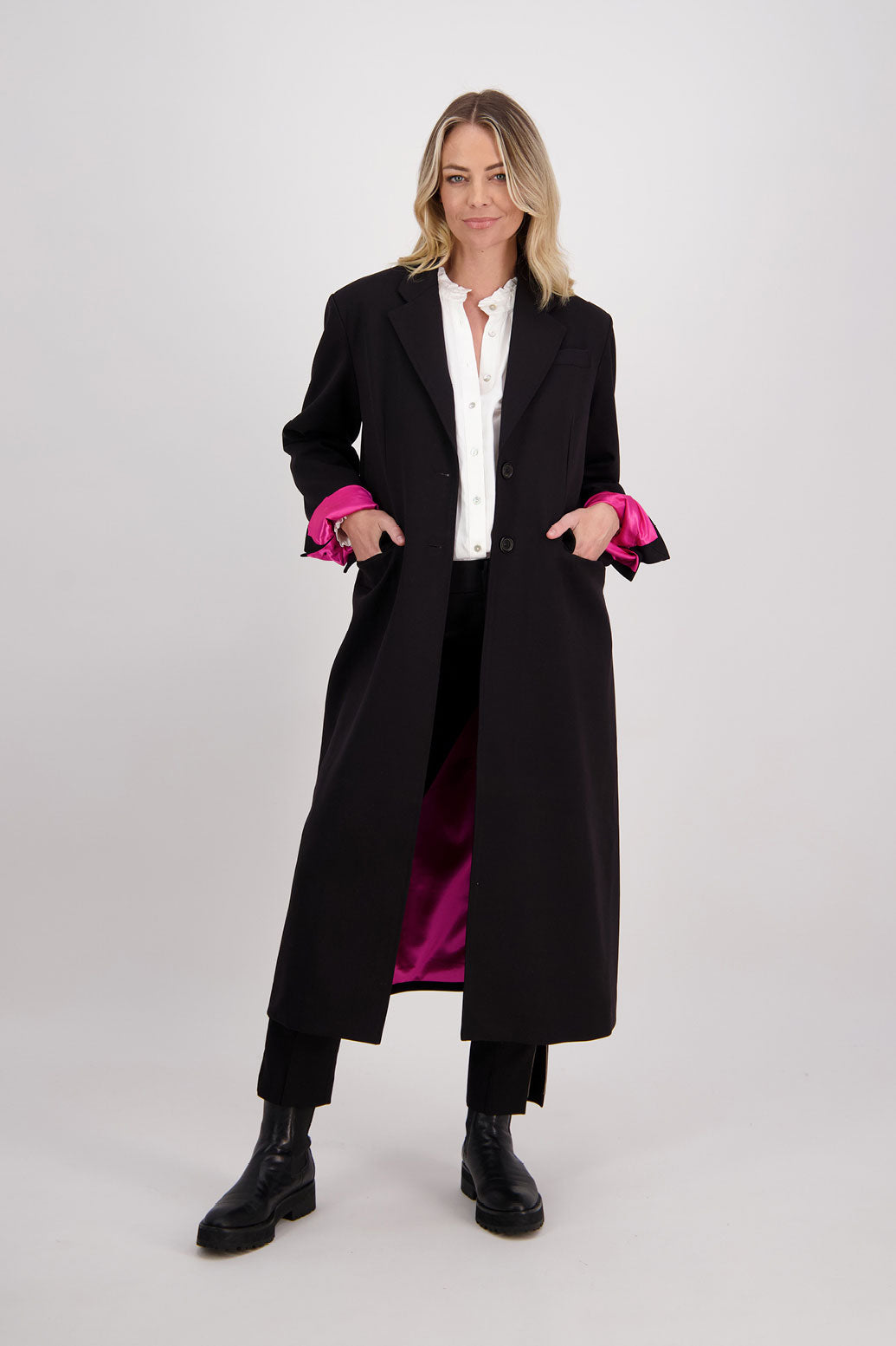 Black tailored long coat with fuchsia lining. Lapel pockets and high back split. Hannah