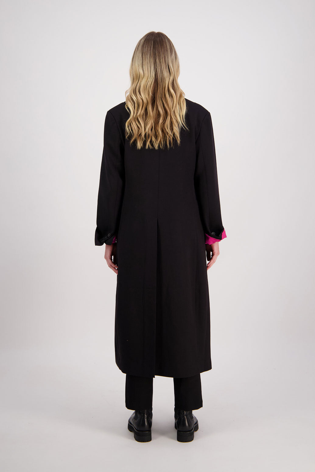 Black tailored long coat with fuchsia lining. Lapel pockets and high back split. Hannah