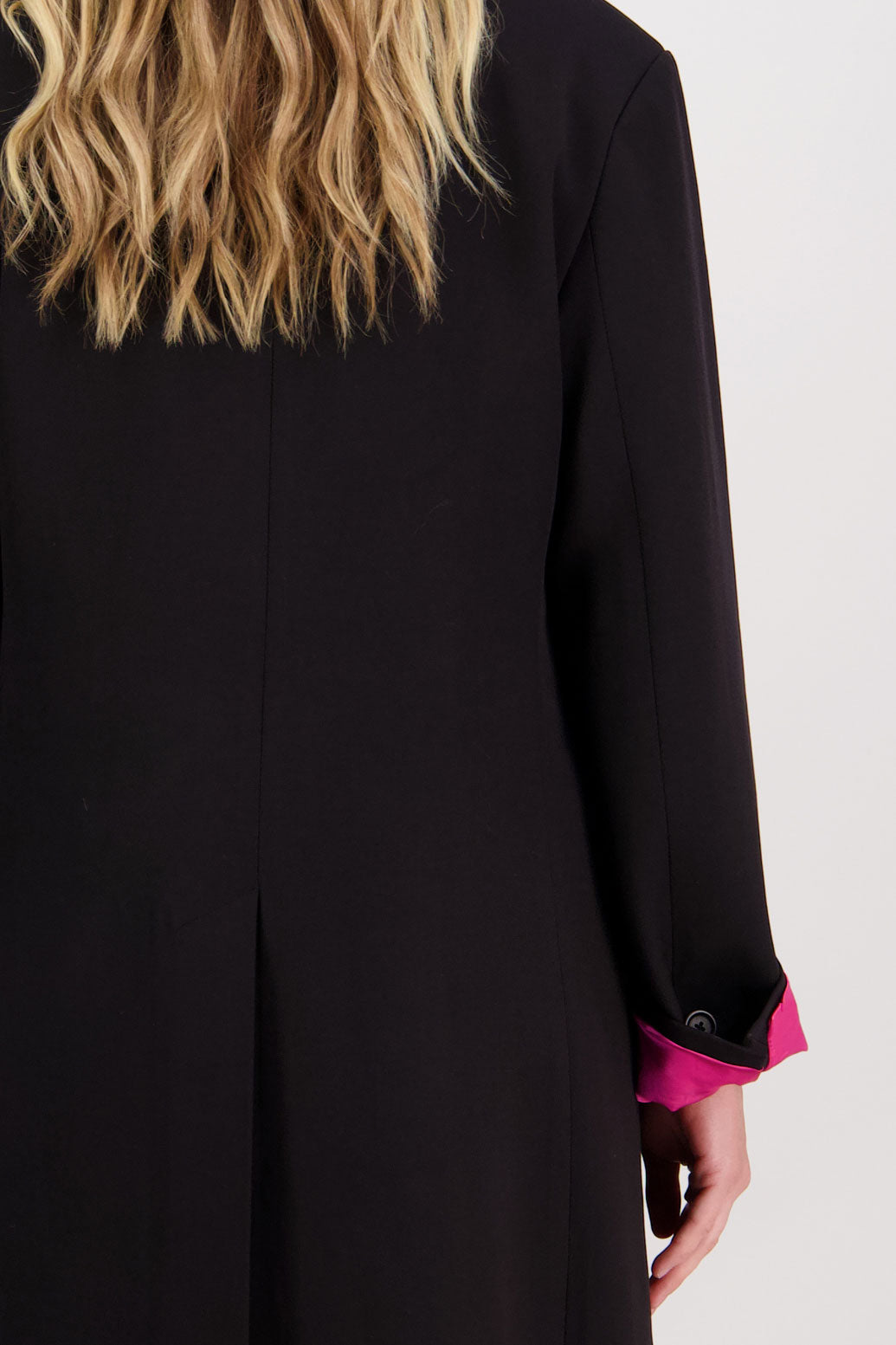 Black tailored long coat with fuchsia lining. Lapel pockets and high back split. Hannah