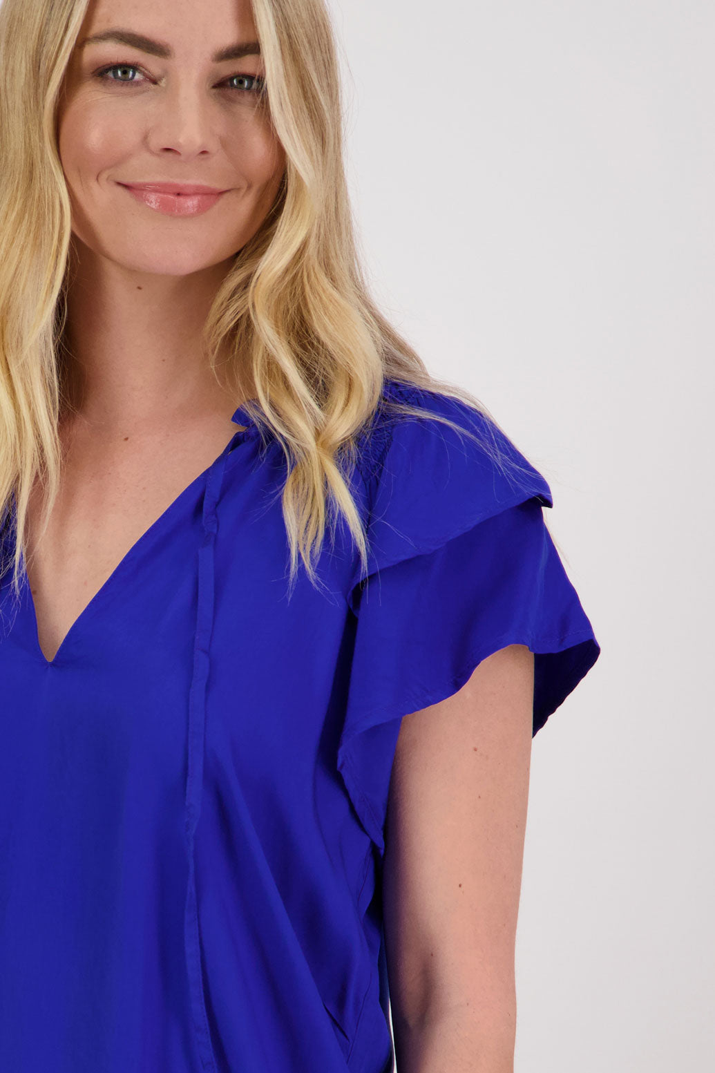 Pansy Womens Short Sleeve top with V Neck and Tie. Double ruffle over the shoulder and shaped hem. Bright Blue