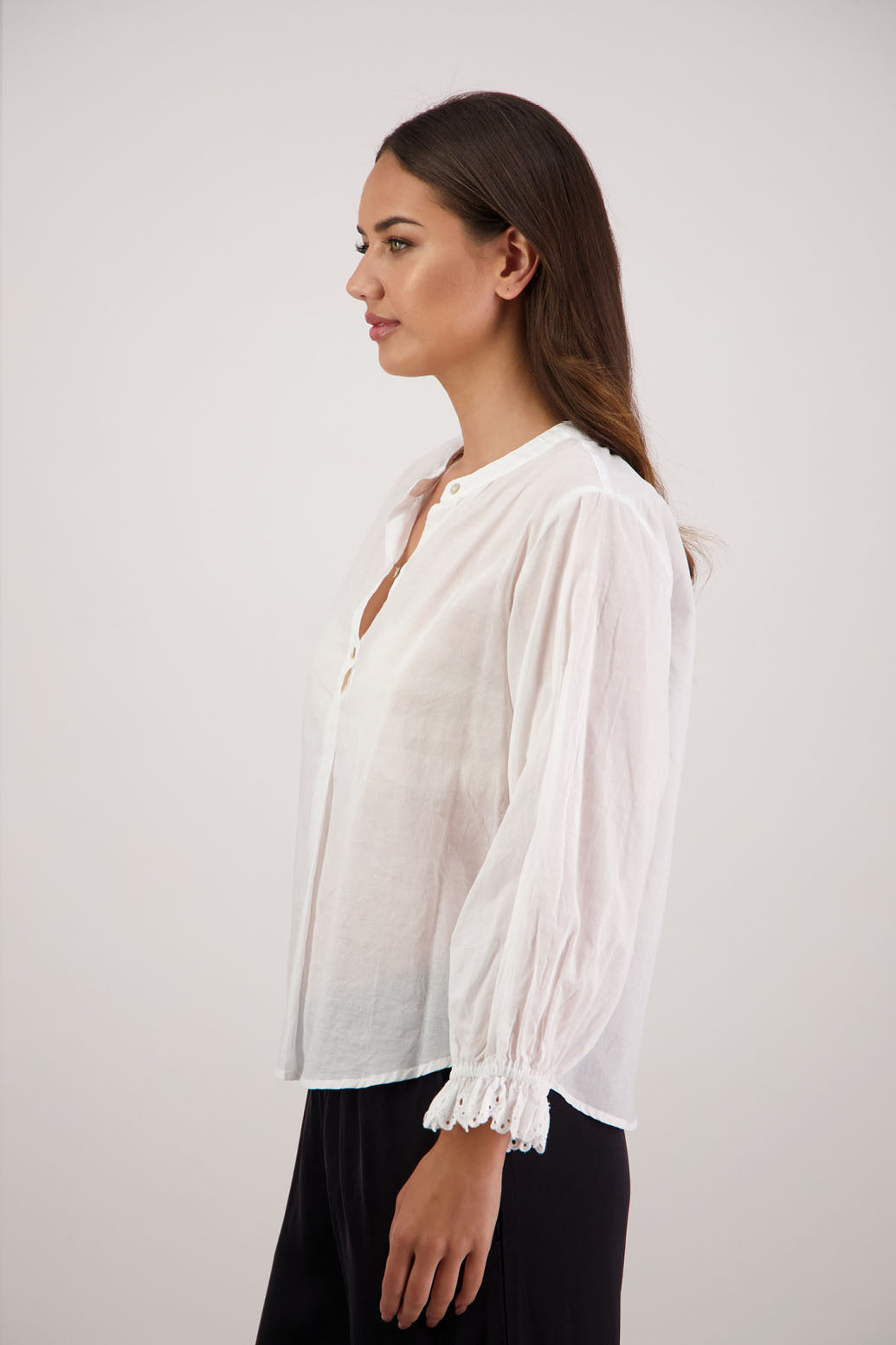 Woman wearing a Randall white shirt with long sleeves against a plain background. Subtle embroidered sleeves.