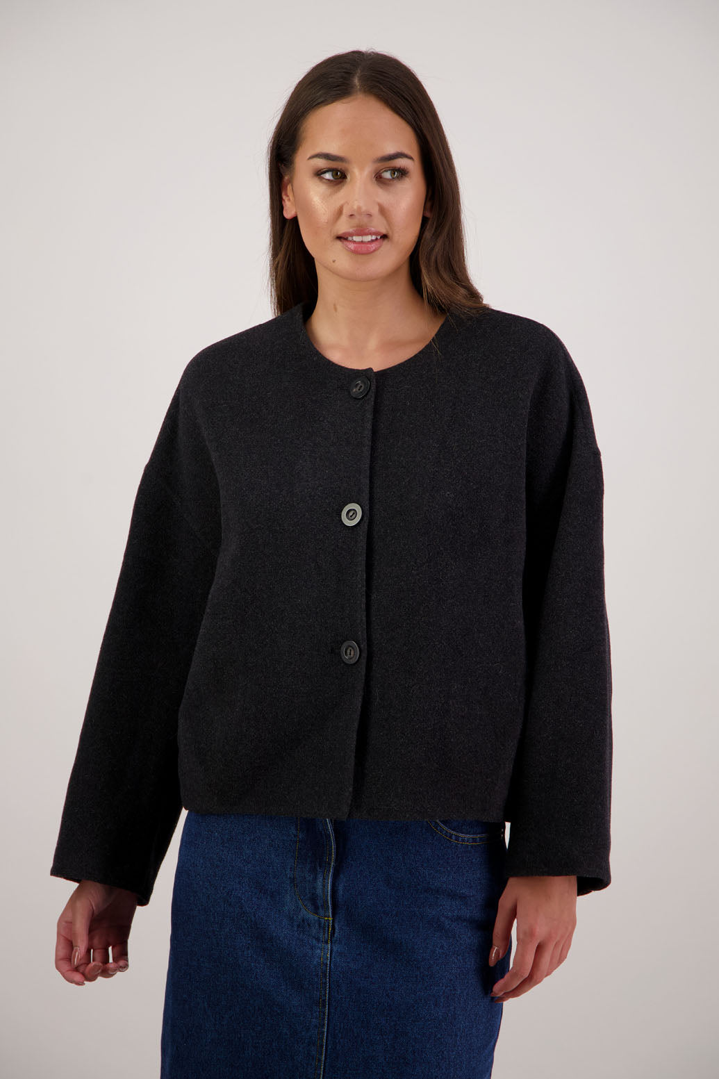 Renee Jacket in Black by Briarwood NZ. Features, no collar, button closure, shaped sleeves, pockets, drop shoulder and dart type pleats on the hem of the jacket