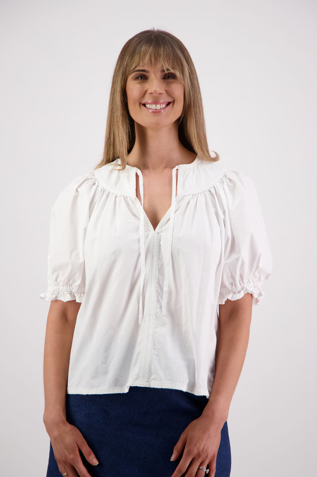 Womens white short sleeve top with soft gathering onto yolk with lace trim around the sleeves, hem + yolk. Briarwood NZ. Cotton Poplin / Lace. Selma